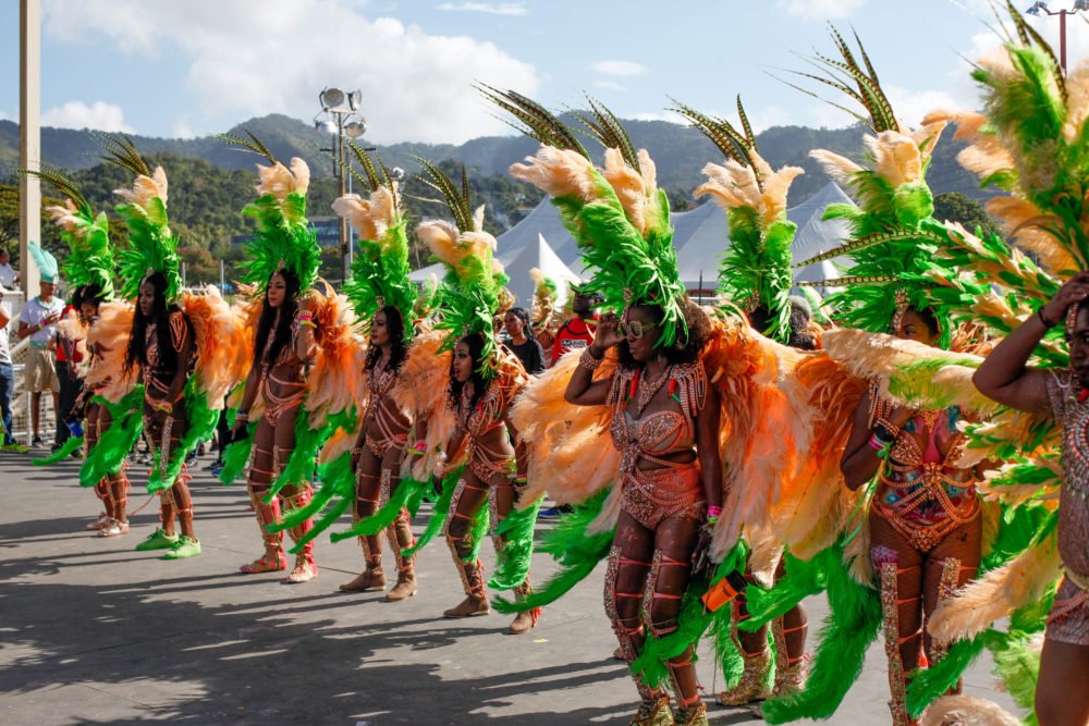 Masqueraders in feathers wait on the stage
