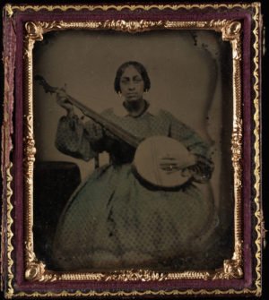 Portrait of a young black woman seated holding nine string banjo